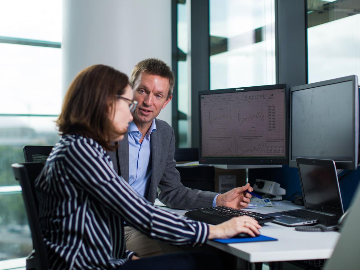 University staff talking whilst at computer