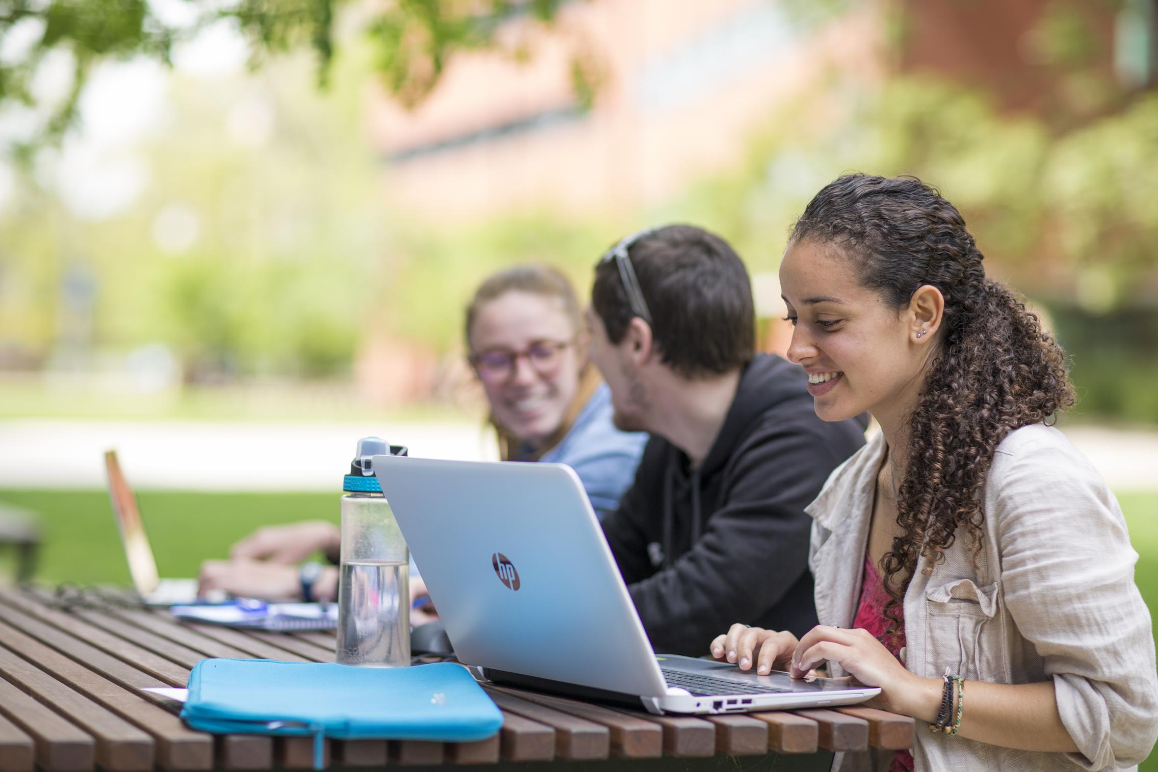 Students studying outside on laptops