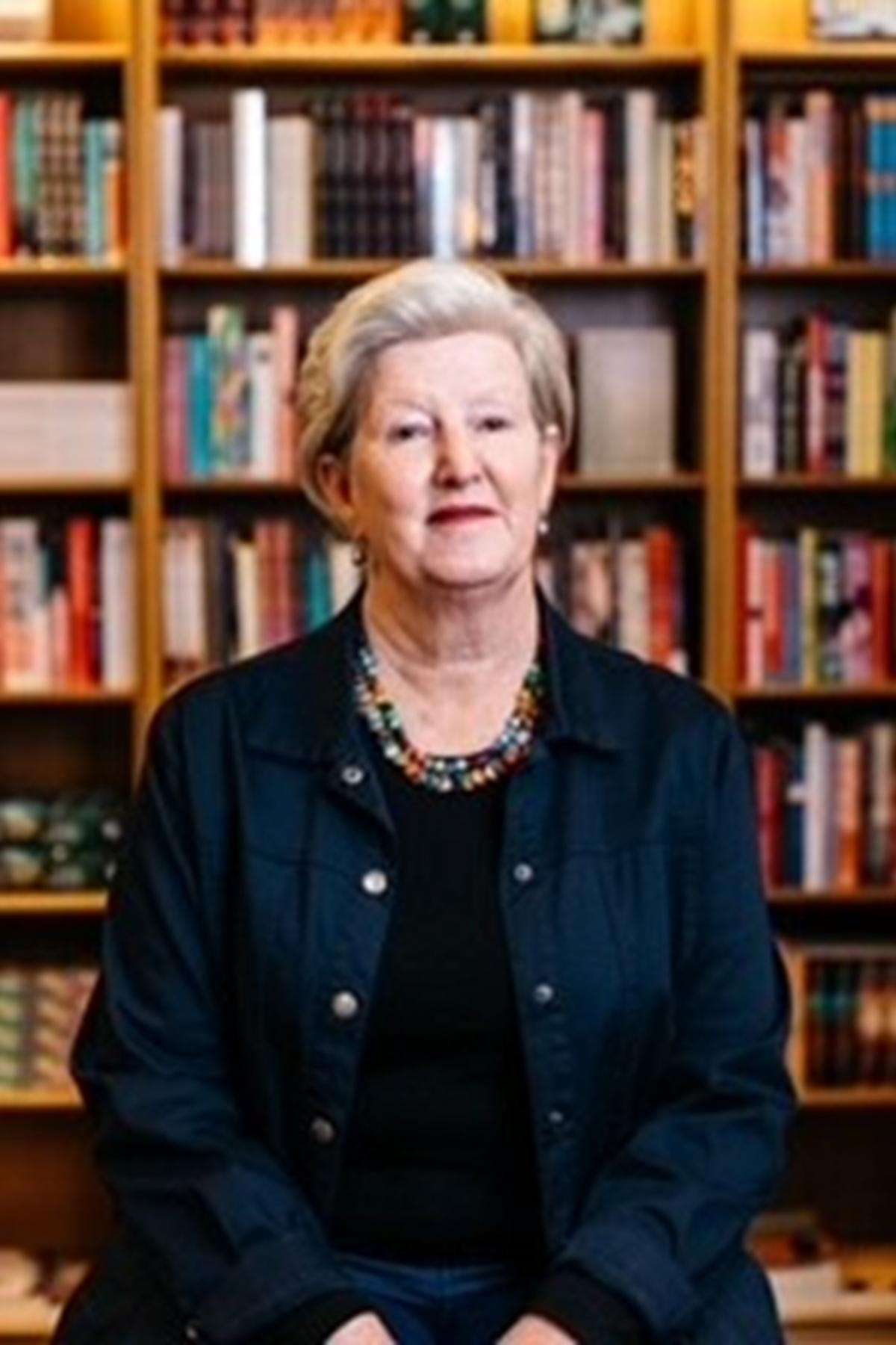 Dr Charmaine Power sitting in front of some bookshelves