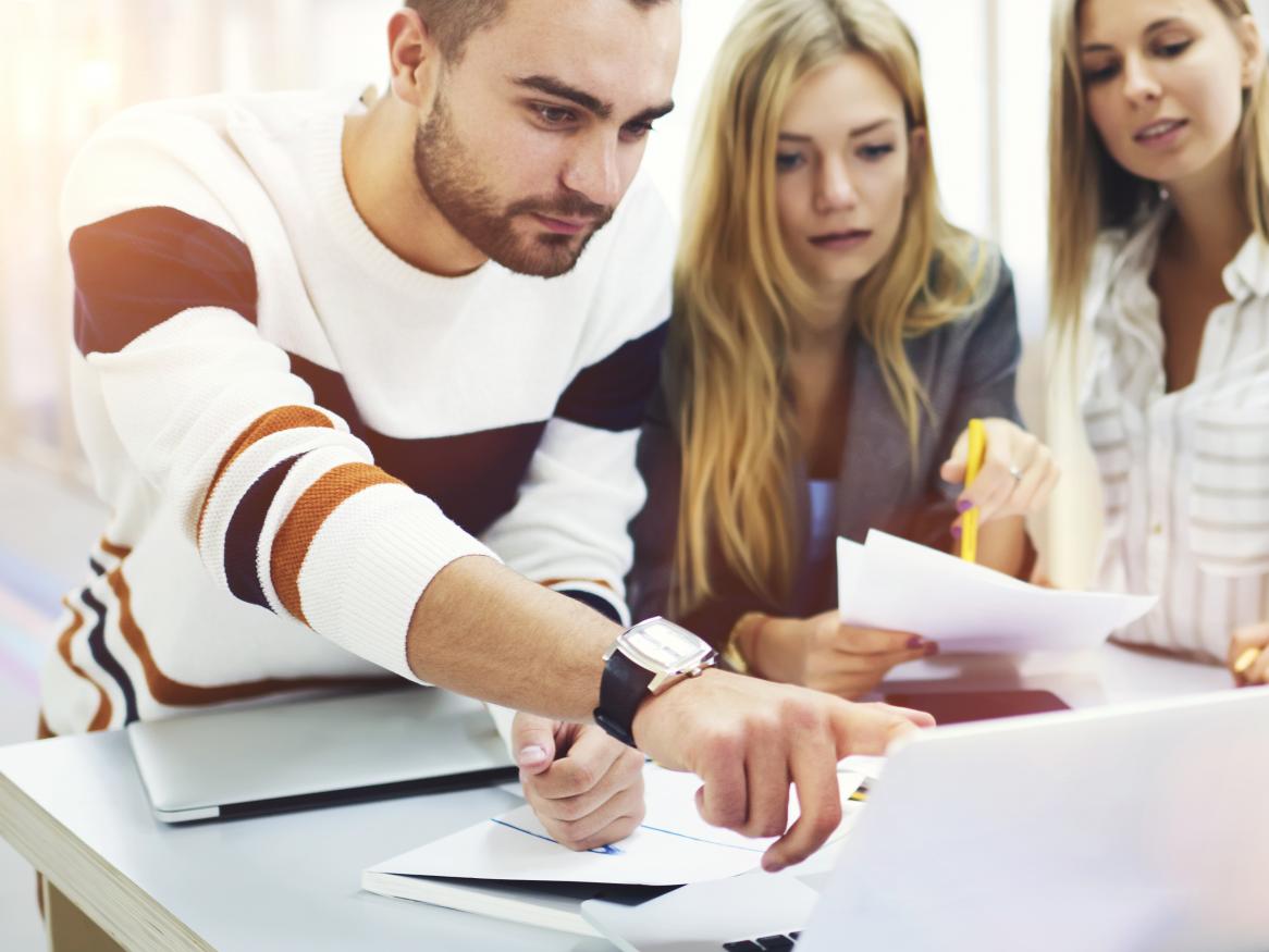 Photo of three early career research students trying to work out where to publish by looking worriedly at a laptop screen