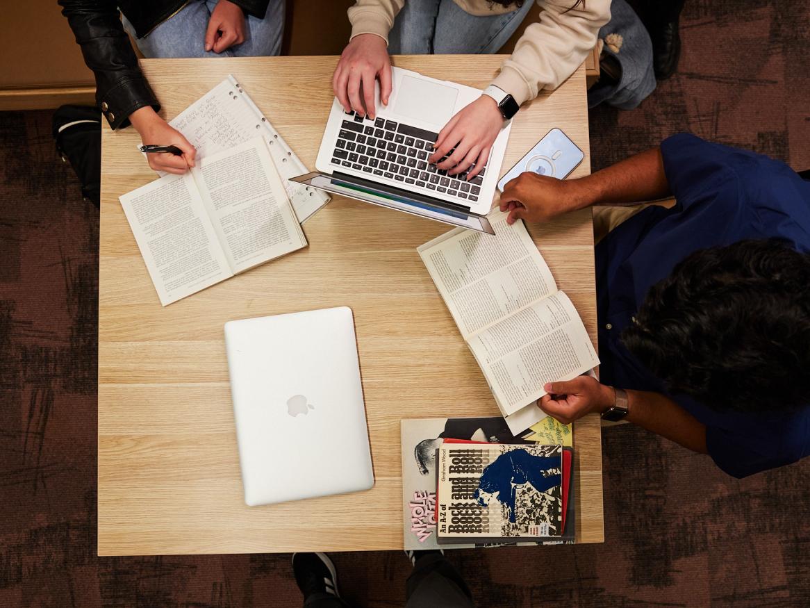 Overhead shot of students with laptop and books on table