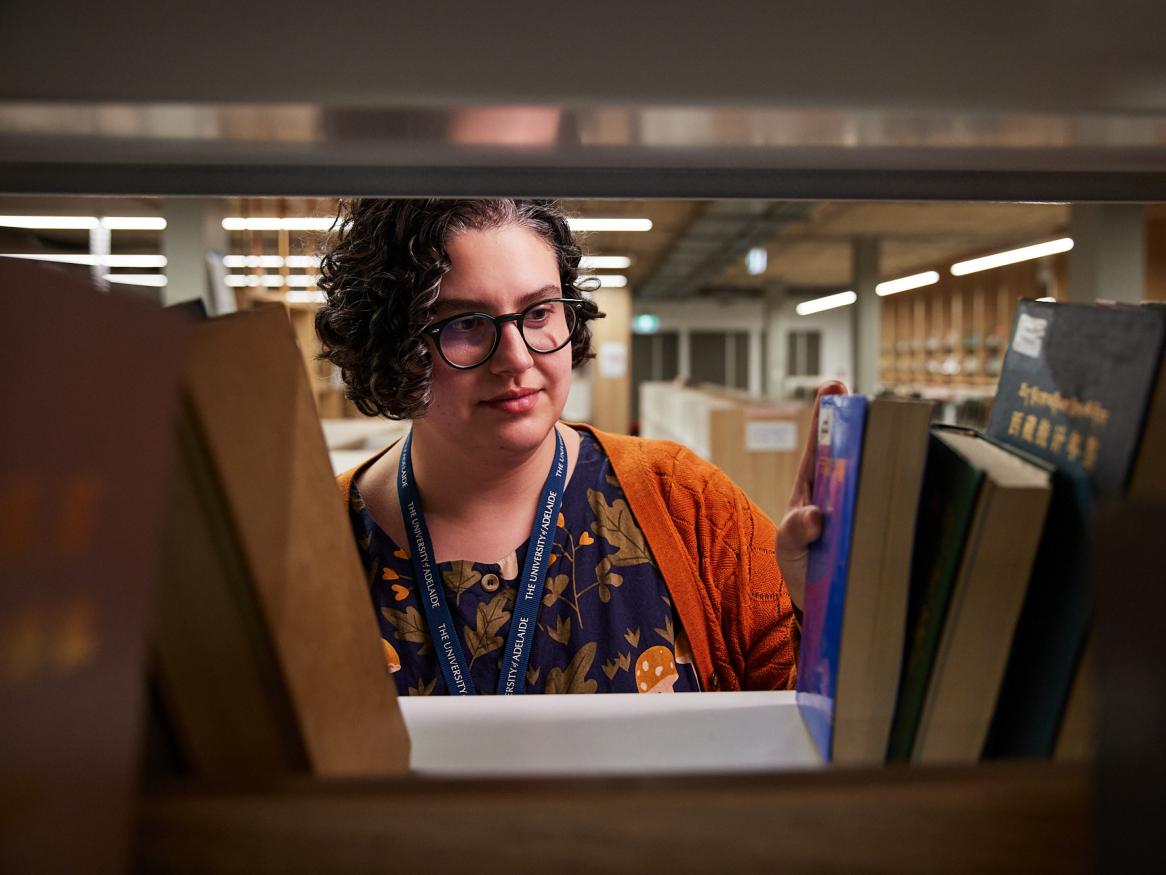 Researcher searching through books in book shelf