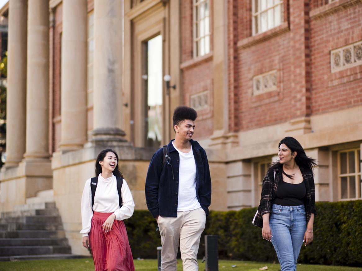 Three students walking past the facade of the Barr Smith Library reading room