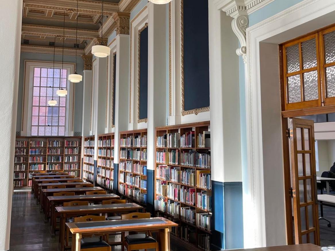 Looking down one aisle of the Reading Room towards a lit up window