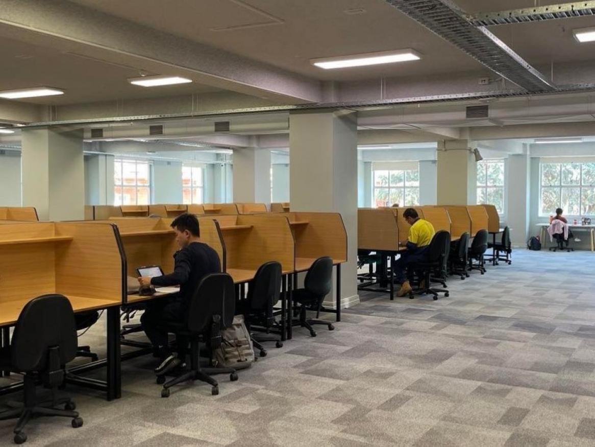 Rows of solo study desks with some students hard at work