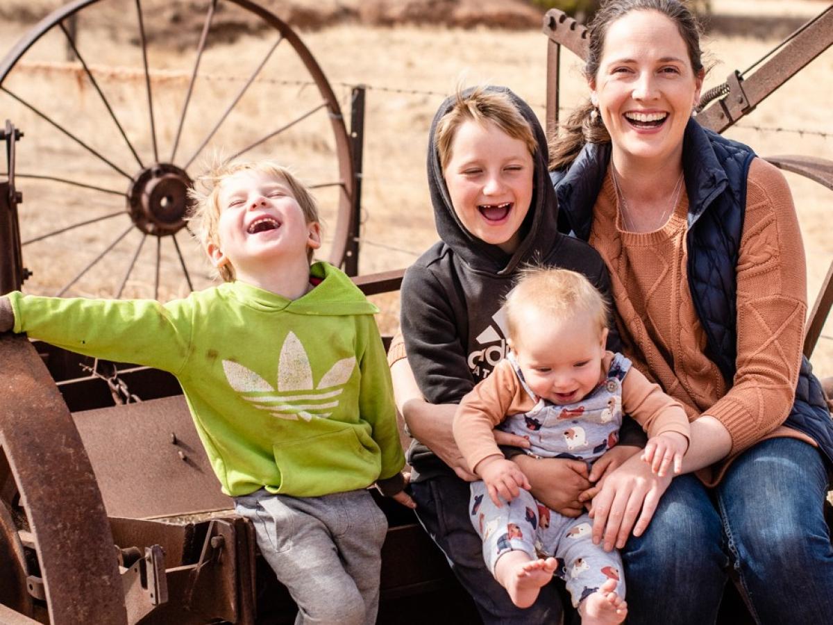 Stephanie Schmidt sits on old farming equipment with her three young sons