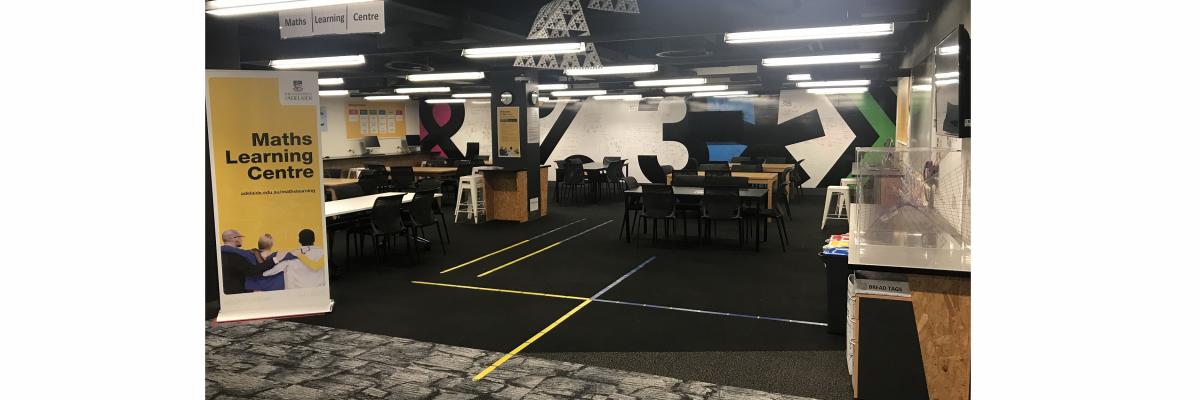 Maths Learning Centre entrance. In the foreground on the floor is a big cross made of yellow and blue coloured tape.