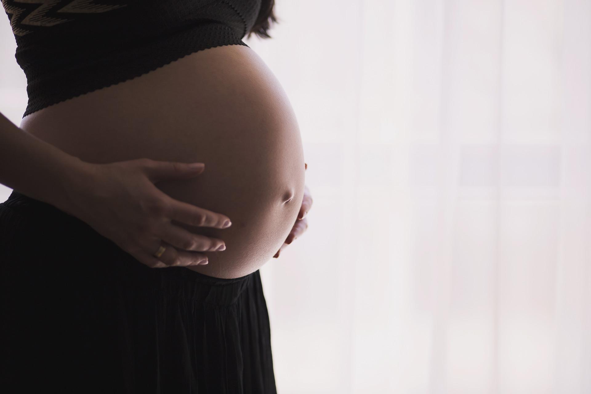 Image of pregnant woman holding her bare belly