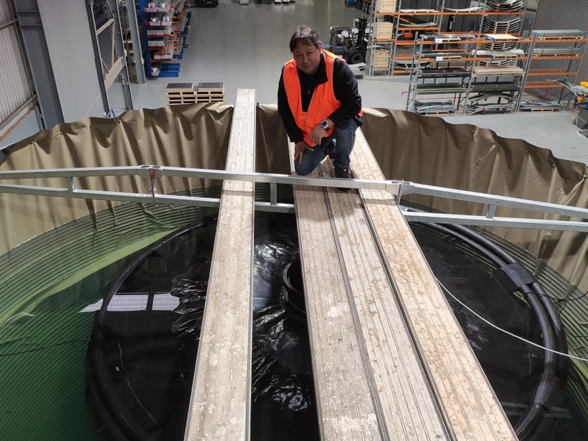 Dr Jose Bellido Caceres sits and smiles over the water tank.