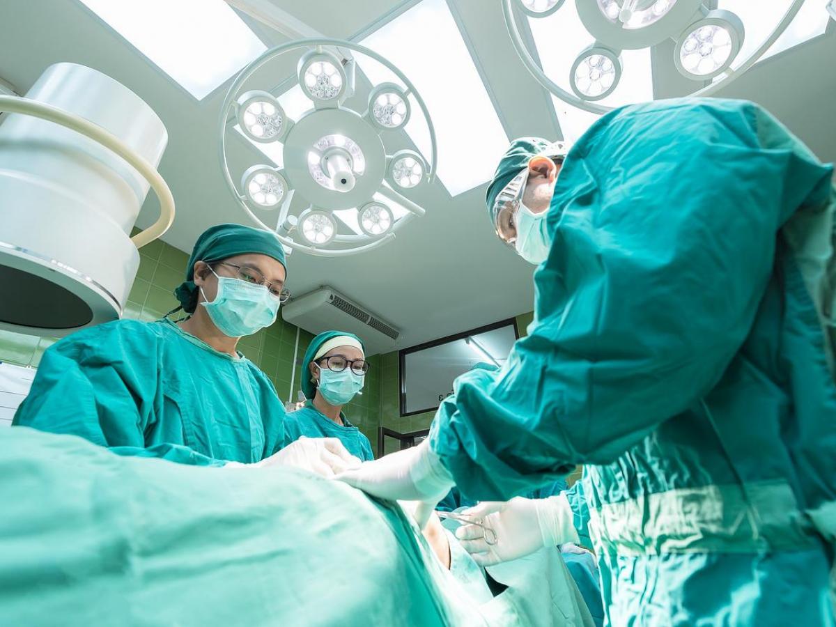 Medical professionals, dressed in scrubs, perform surgery in a hospital.