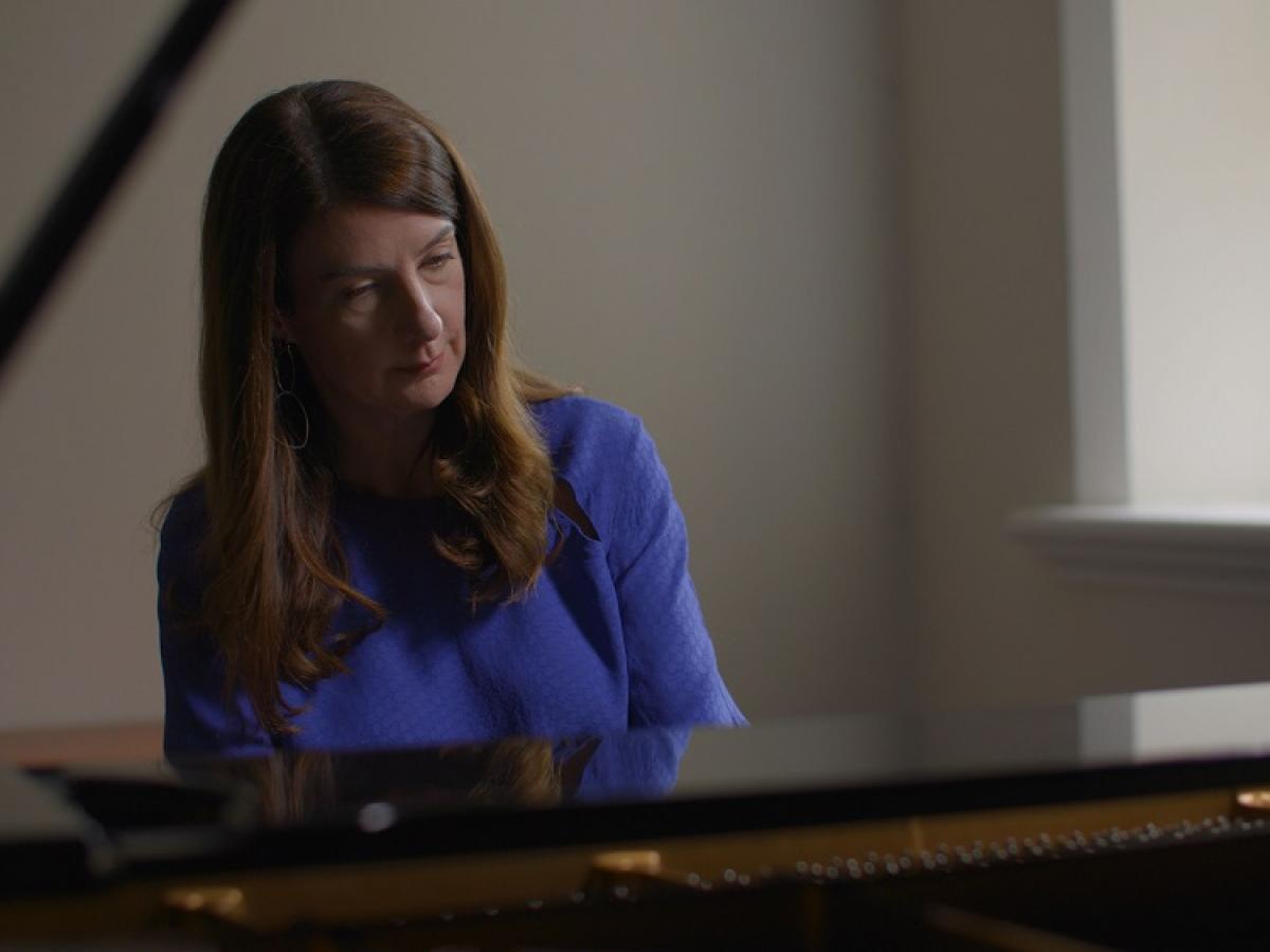Anna Goldsworthy sits at and plays a piano.