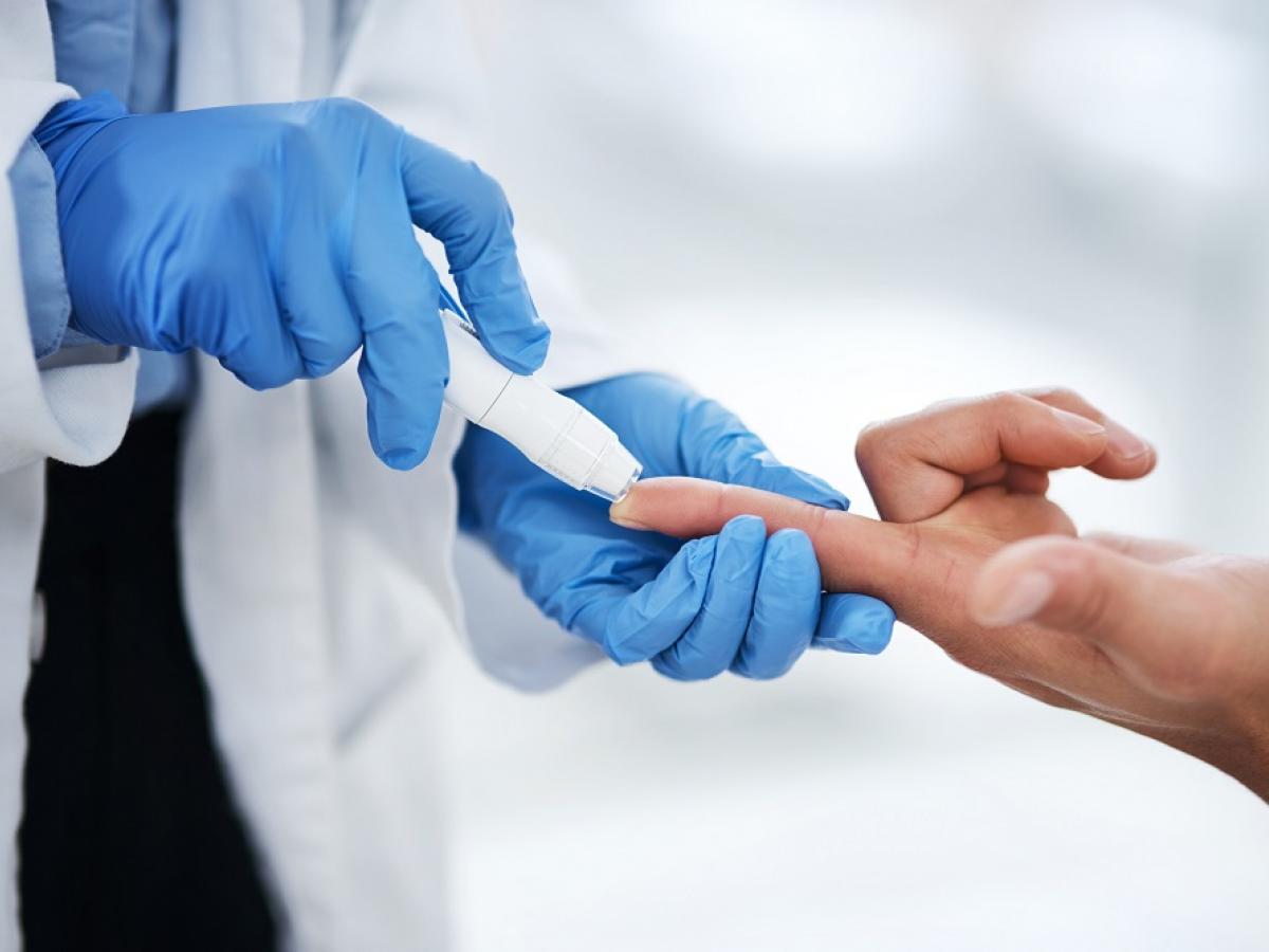 A medical professional gives a patient a finger-prick test.