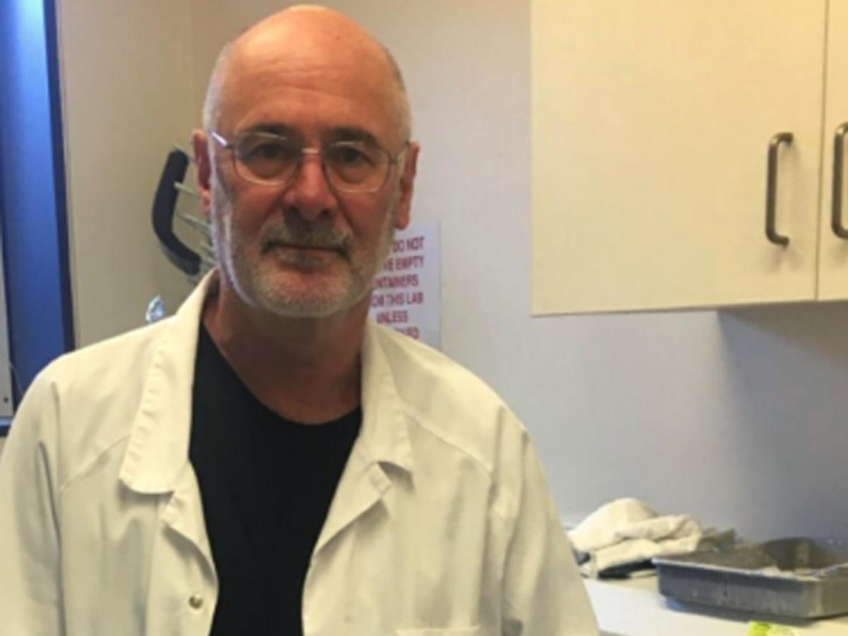 Professor Roger Byard wears a lab coat and smiles into the camera.