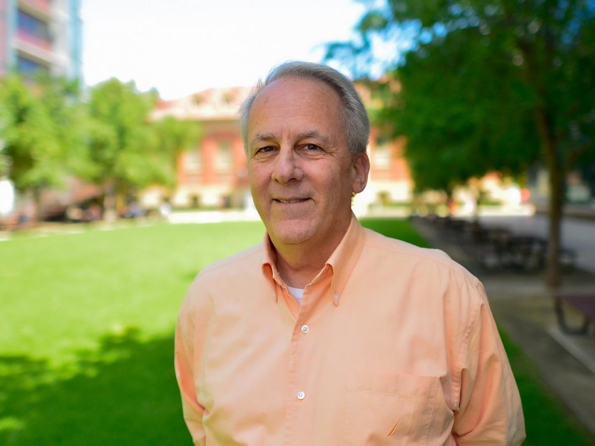 Professor David L. Adelson, outdoors, smiles into the camera.