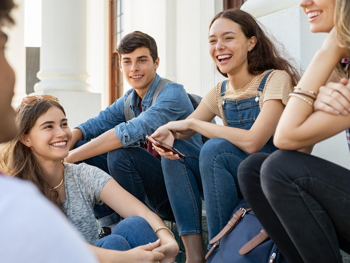 A group of teenagers sit and smile.