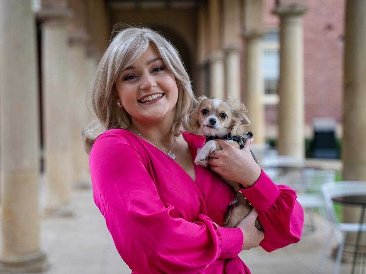 April Beak, playing Elle Woods, holds a Chihuahua.