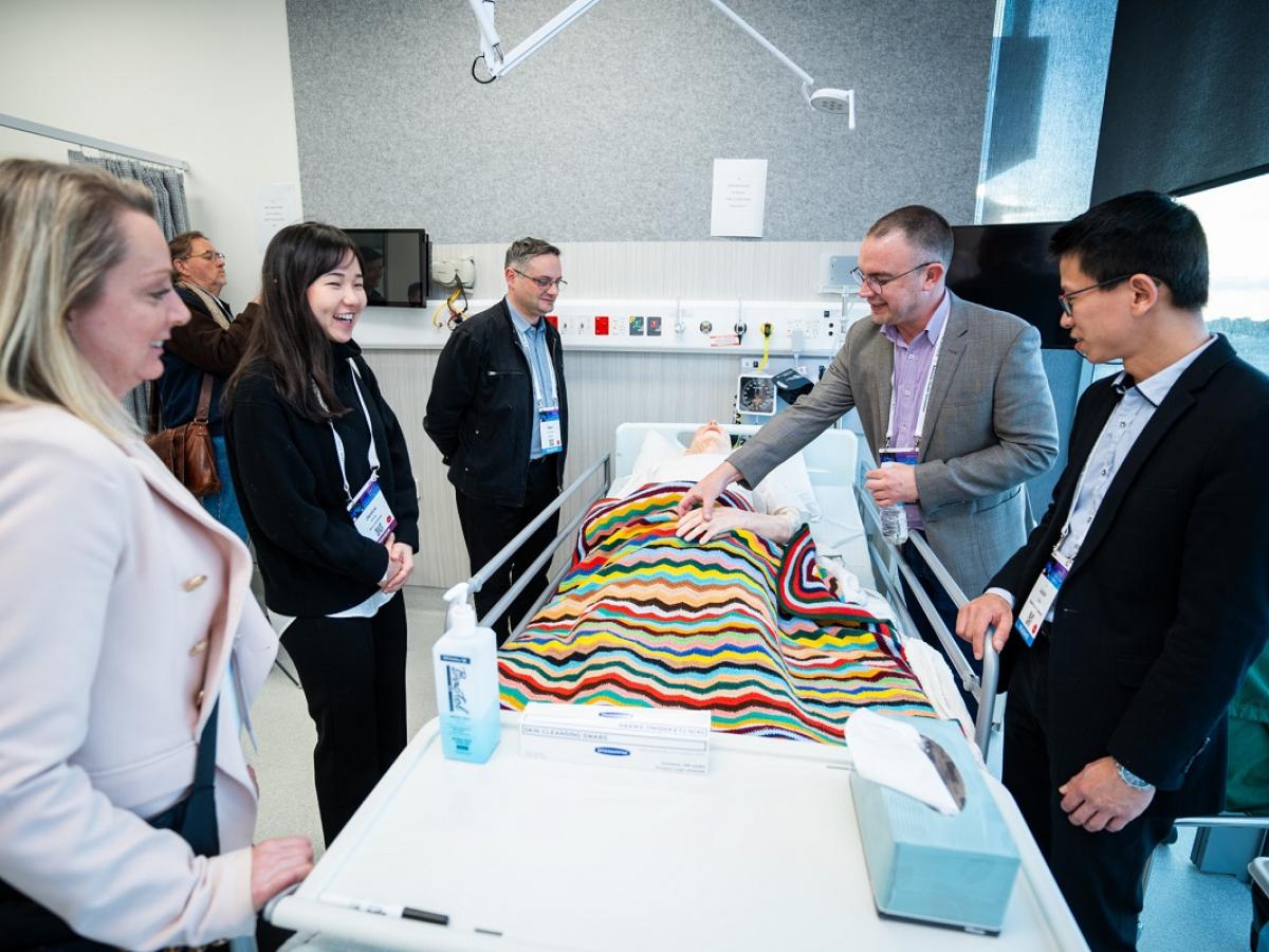 Photo of Associate Professor Adam Montagu showing experts a manikin used for teaching at Adelaide Health Simulation.