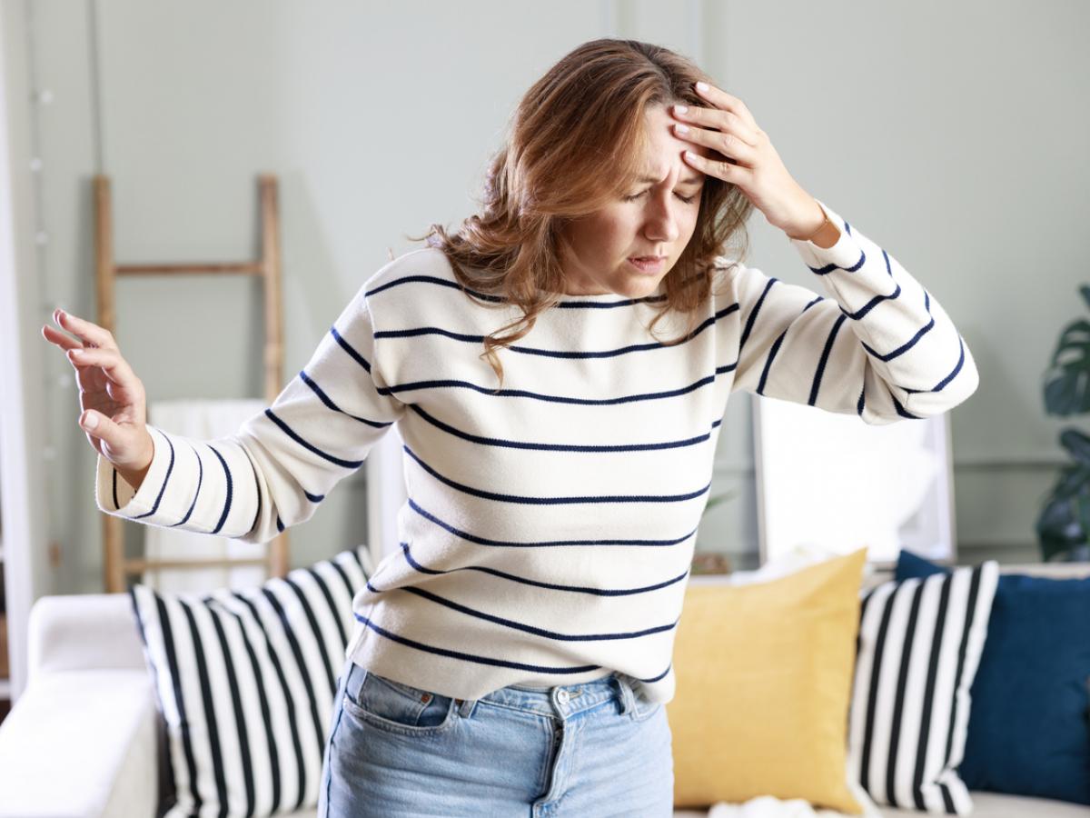 A woman with brown hair and a striped white and black jumper looks dizzy after standing up.