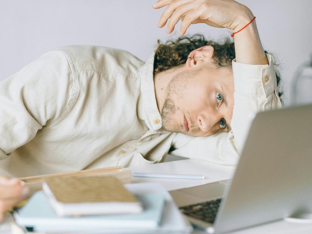 A man lays on his arm at a desk