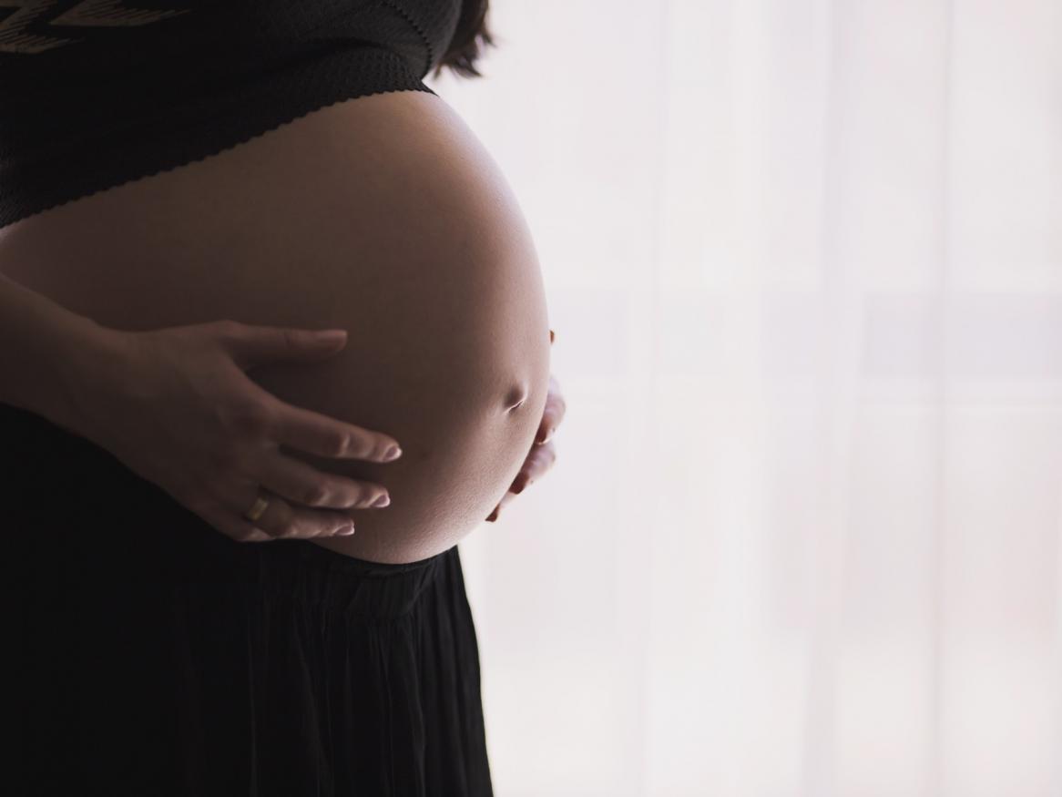 Image of pregnant woman holding her bare belly