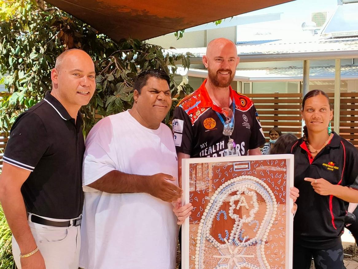 AKction Reference Group members Jared and Rhanee presenting a memorial Kidney art piece to Kanggawodli Aboriginal Hostel and dialysis service at the launch of the Cultural Bias document - L to R Wade Alan, Jared Katinyeri, Kurt Towers and Rhanee Lester.