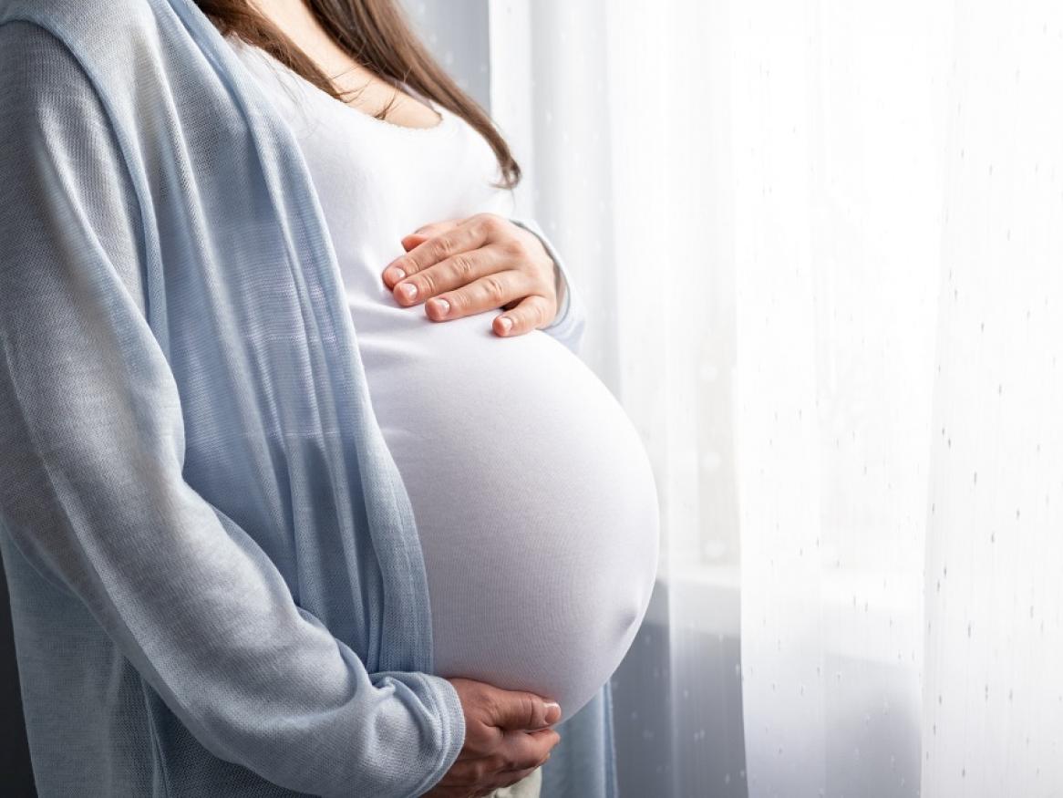 A pregnant woman cradles her stomach.