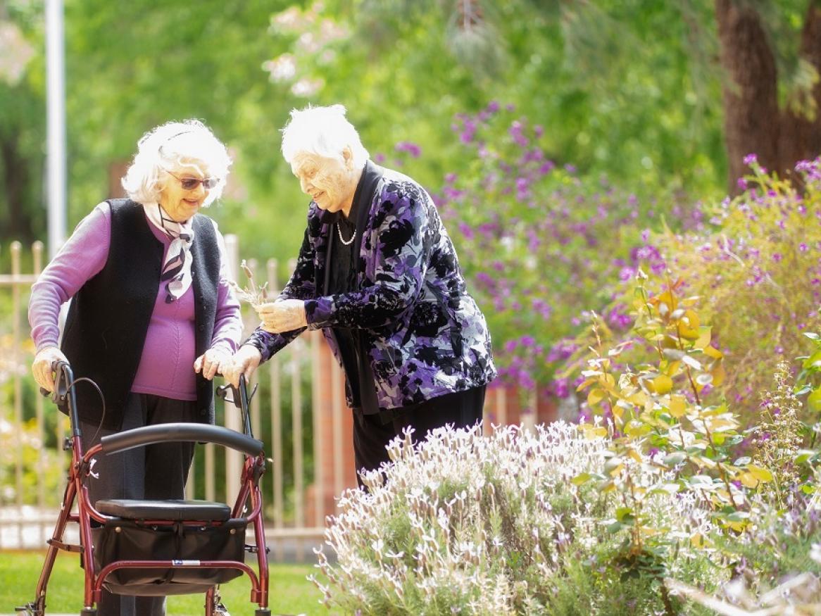 Two Resthaven residents walk through a garden and talk to each other.