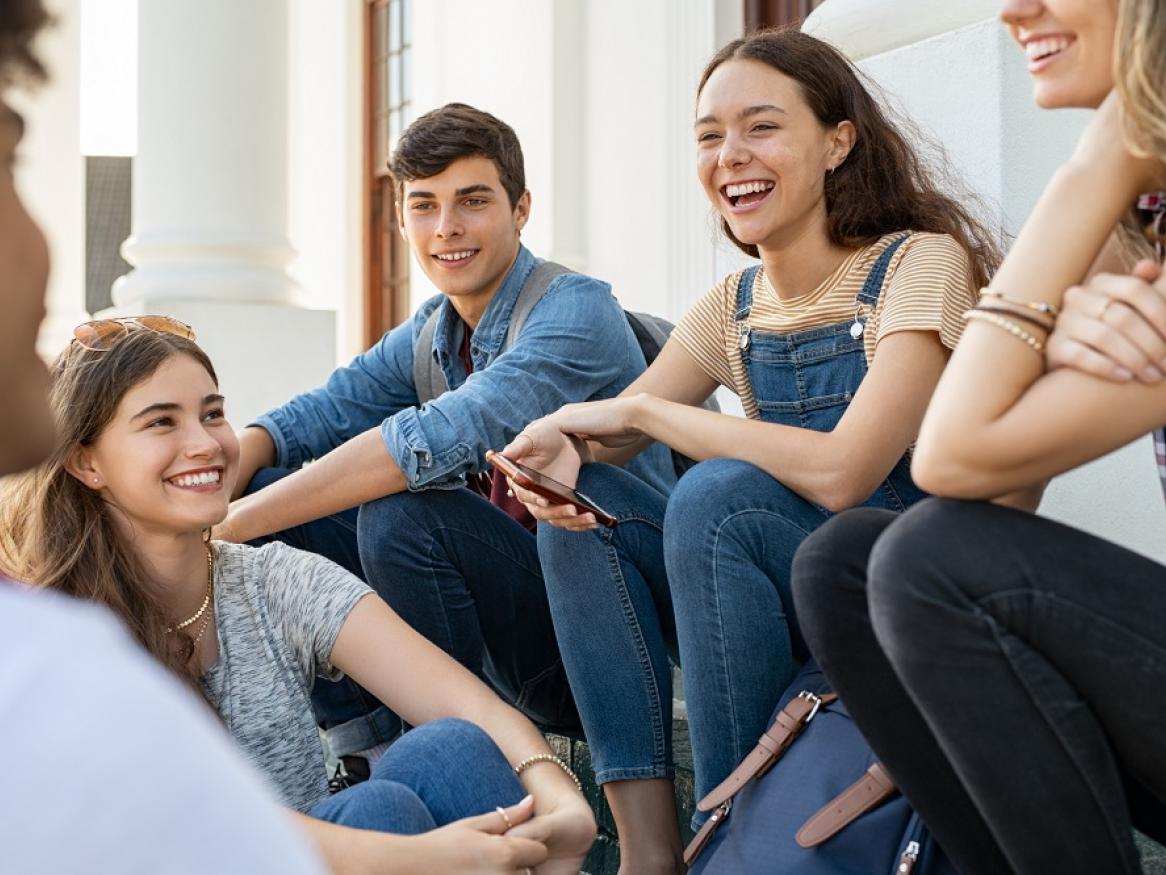 A group of teenagers sit and smile.