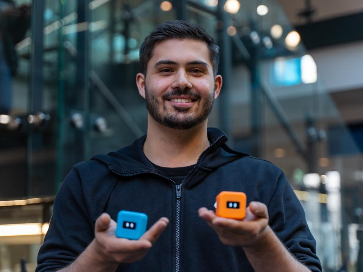 Sam Messina holding an Ortomi, a robot companion he co-created.