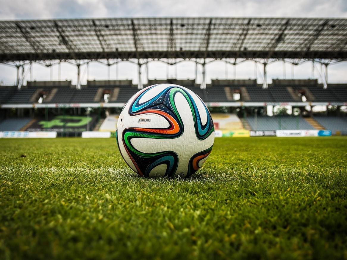 A soccer ball sits on the grass in empty arena.