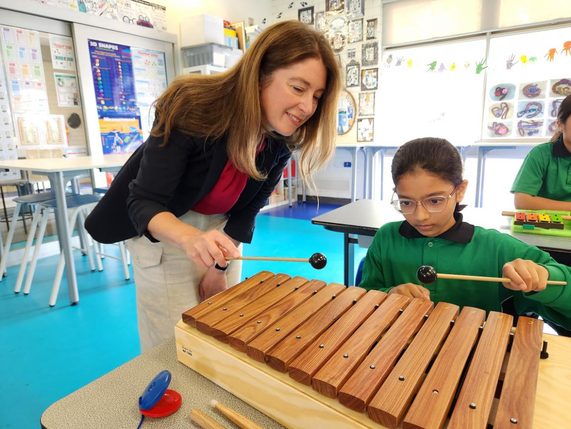 Emily Dollman playing an instrument with a student