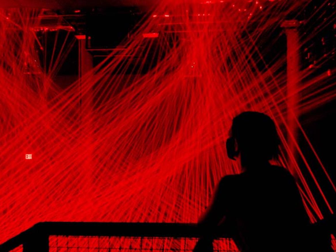 a person looking at a room of red lasers