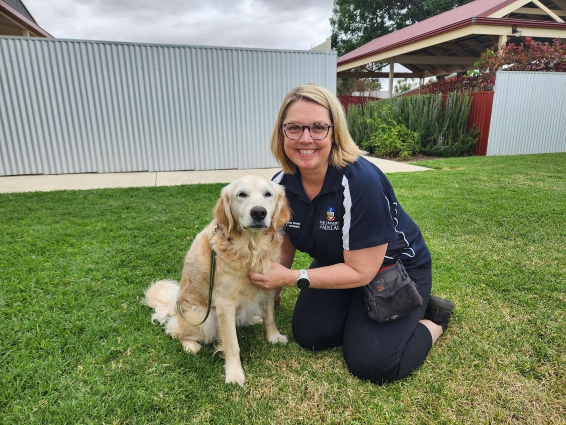 Photo of Tracey Taylor with a dog on the grass.