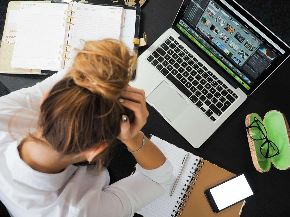 A woman sits at a computer, stressfully 