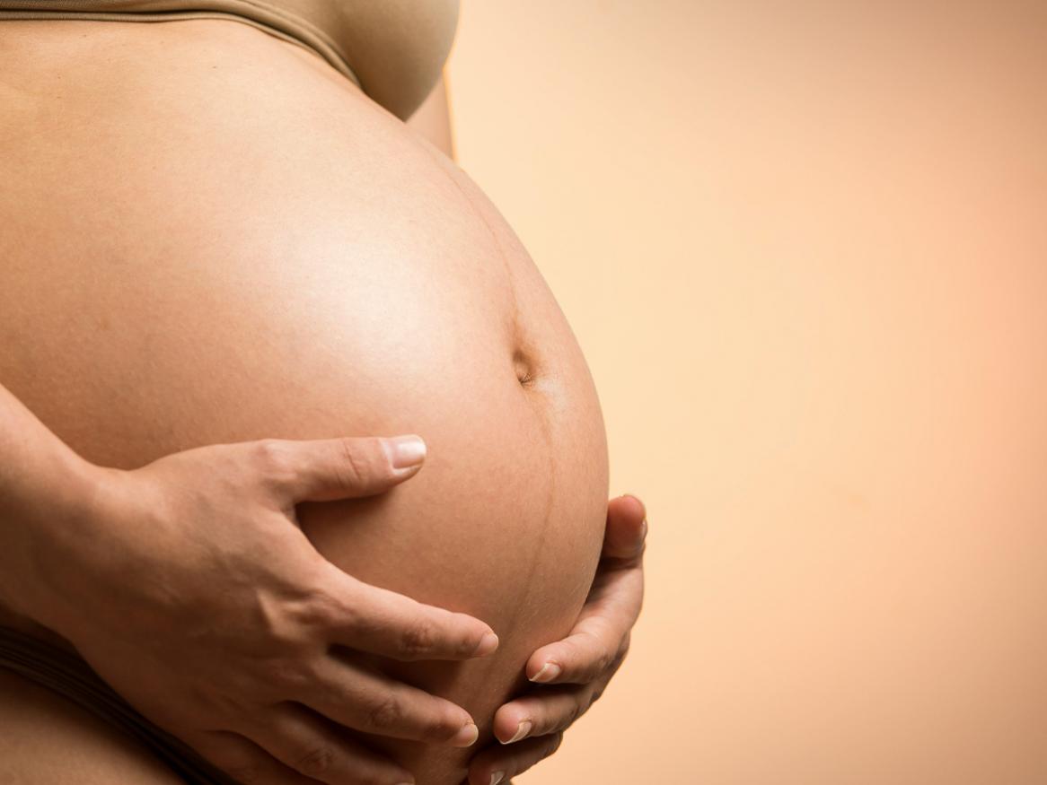 A woman holds her pregnant belly