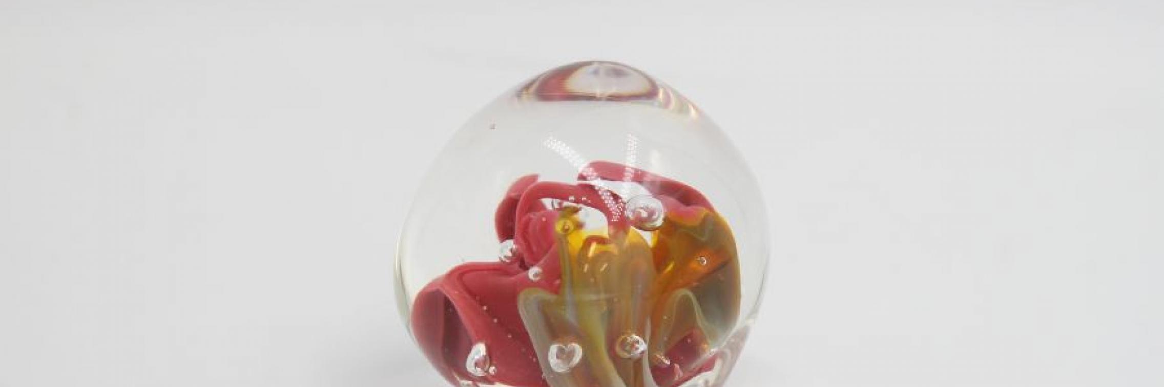 Image of a glass artwork. A glass sphere with gold and pink colours in its centre.
