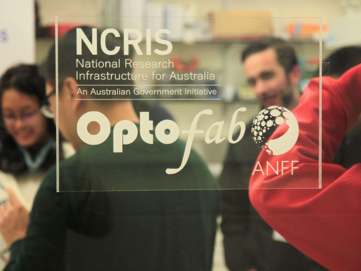 Photo taken trough glass door of the fabrication lab with the NCRIS and Optofab Logo