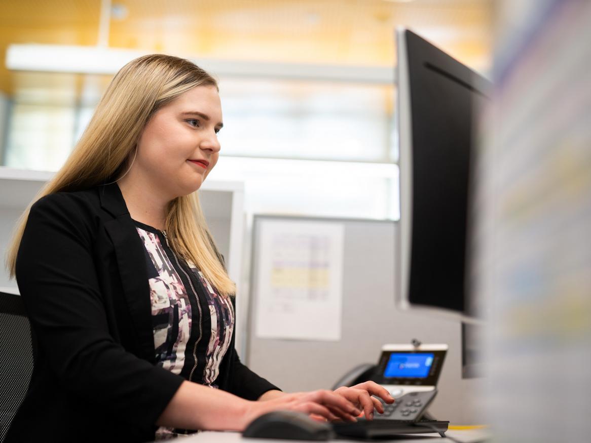 Blonde woman in an office cubicle working on computer