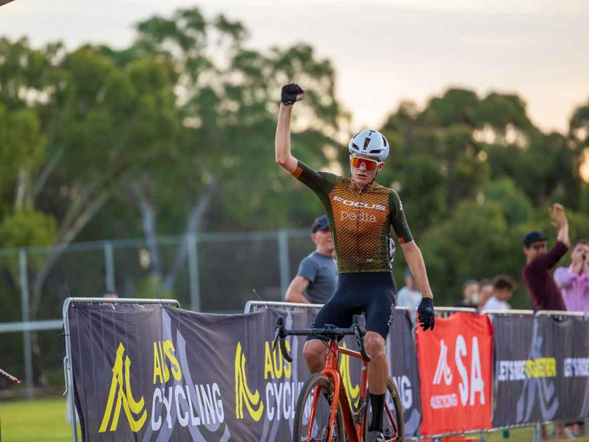 Cyclist on a bike, celebrating with fist pumped up in the air. 