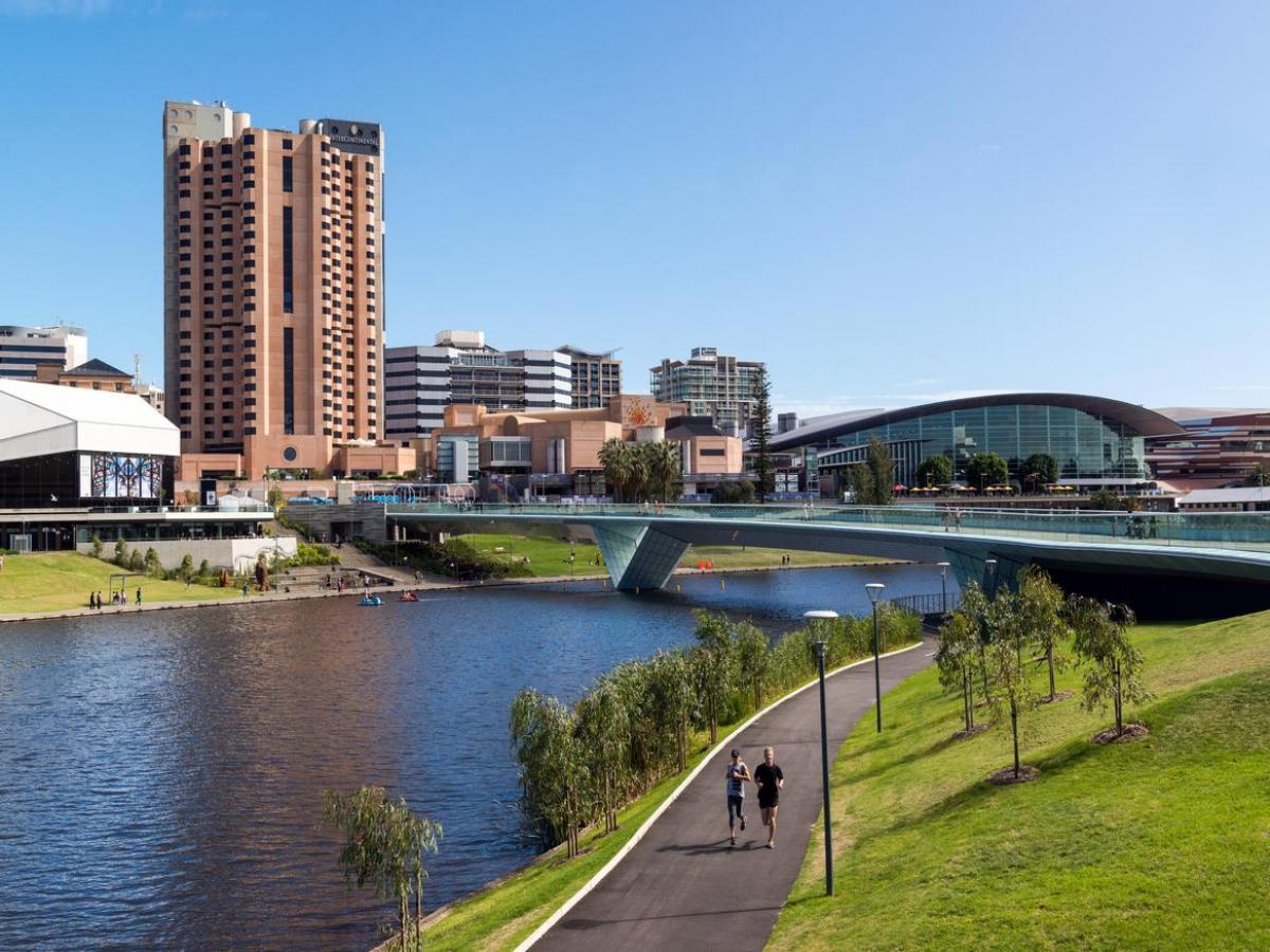 Photo of River Torrens in Adelaide with buildings in the background and people running.