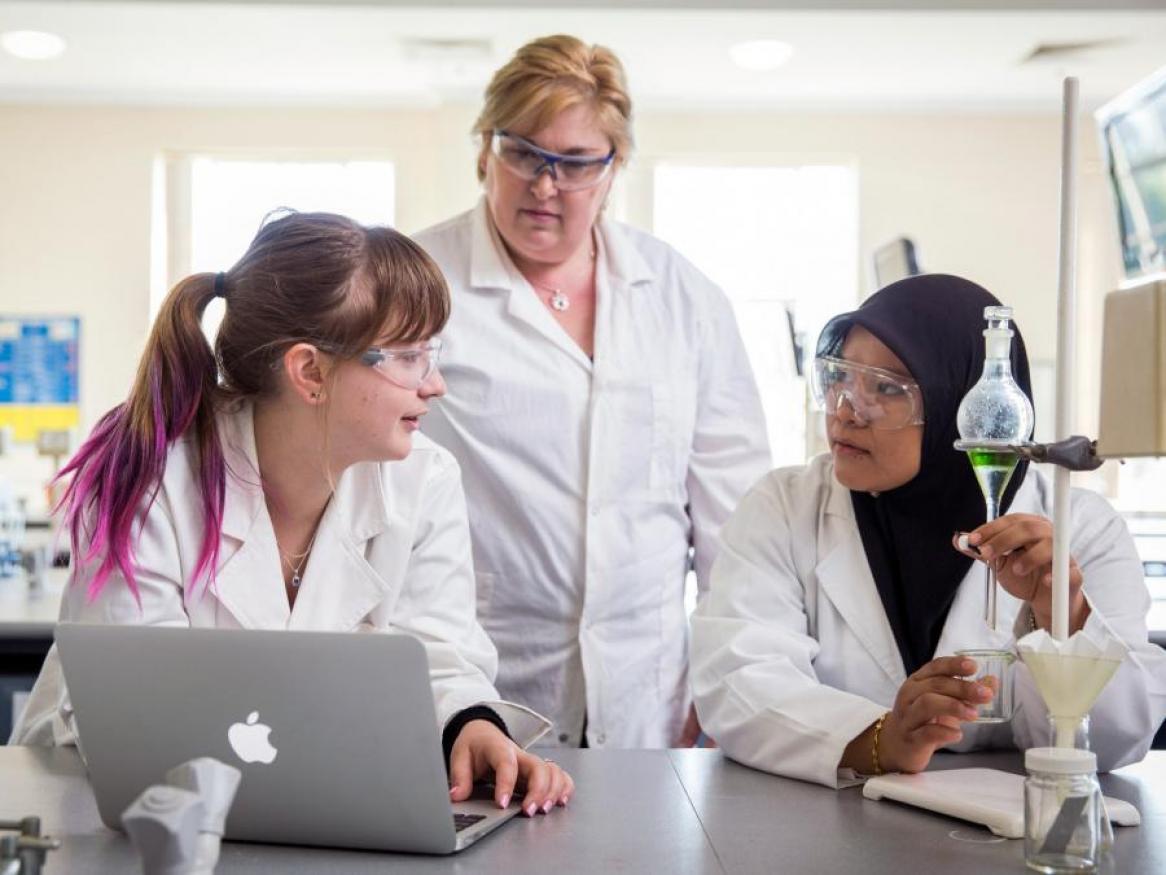 Two students, with lecturer, in a science lab. 