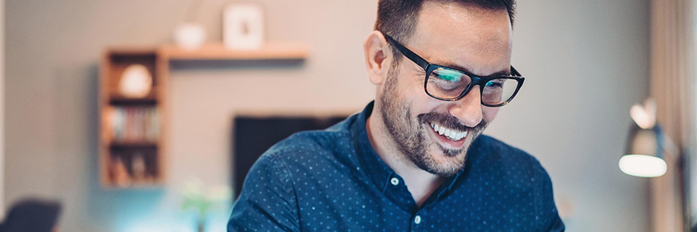 Male looking down and at a laptop and smiling