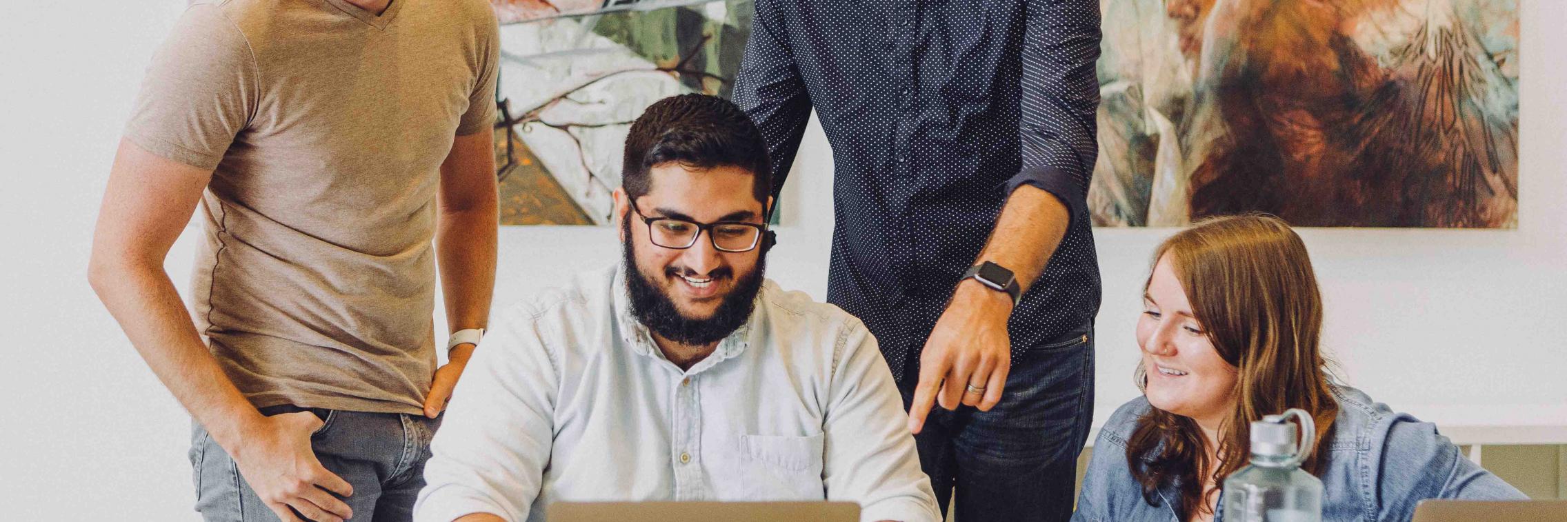 A group of people collaborating around a computer