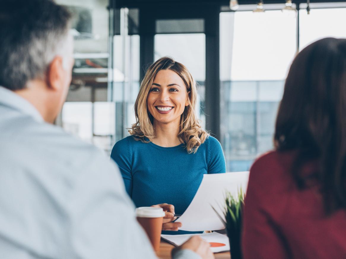 Female smiling at a desk, meeting with a couple