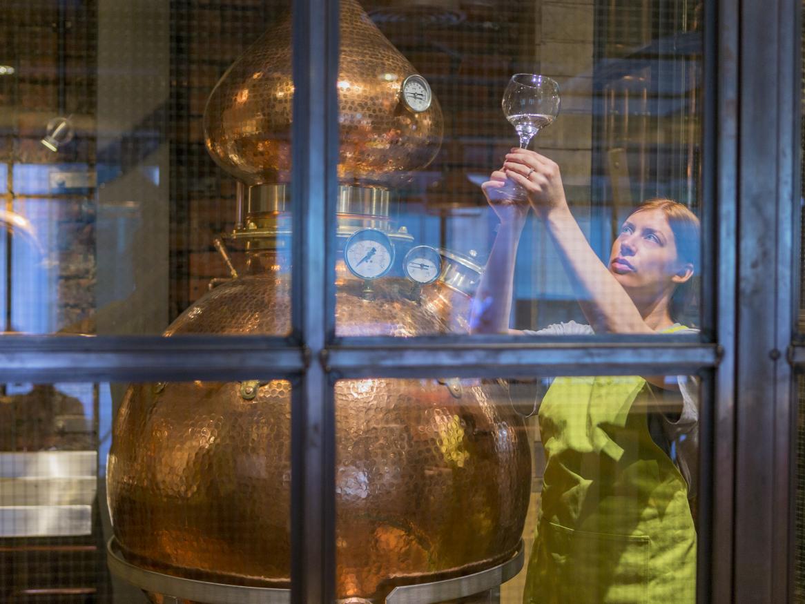 Female looking at a glass in a distillery 