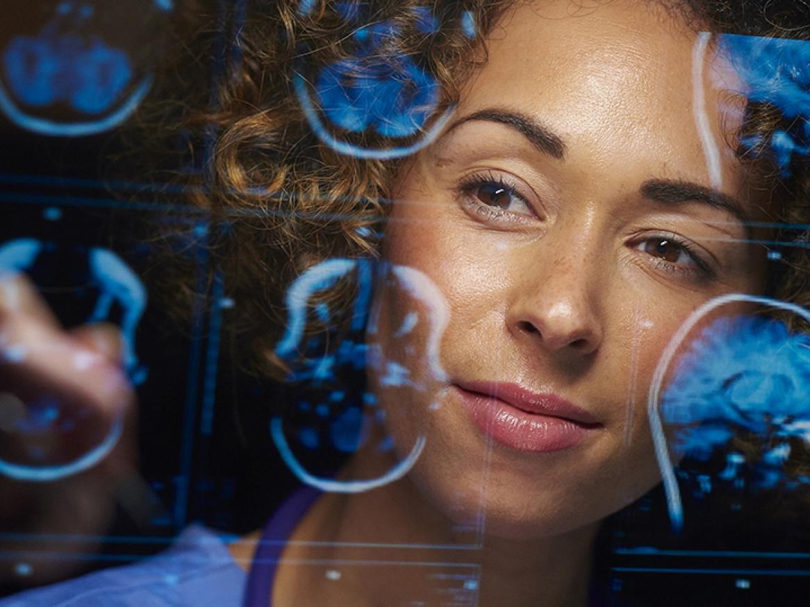 Young female medical professional looking at digital brain scans