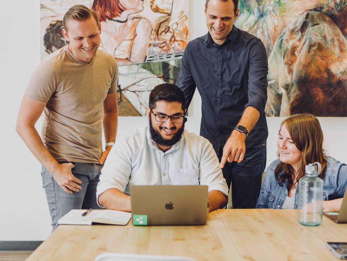 A group of people collaborating around a computer