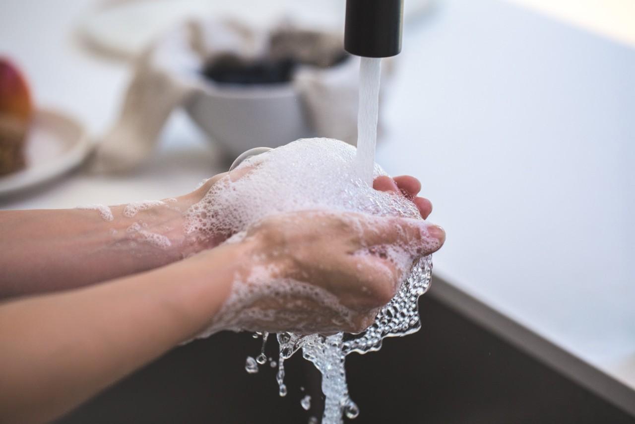 person washing their hands with water and hand soap