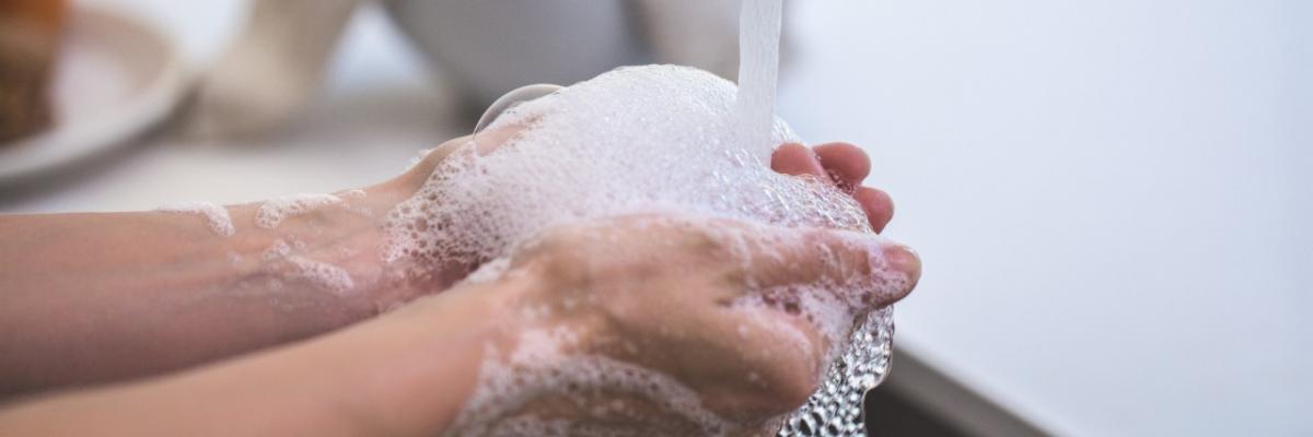 person washing their hands with water and hand soap