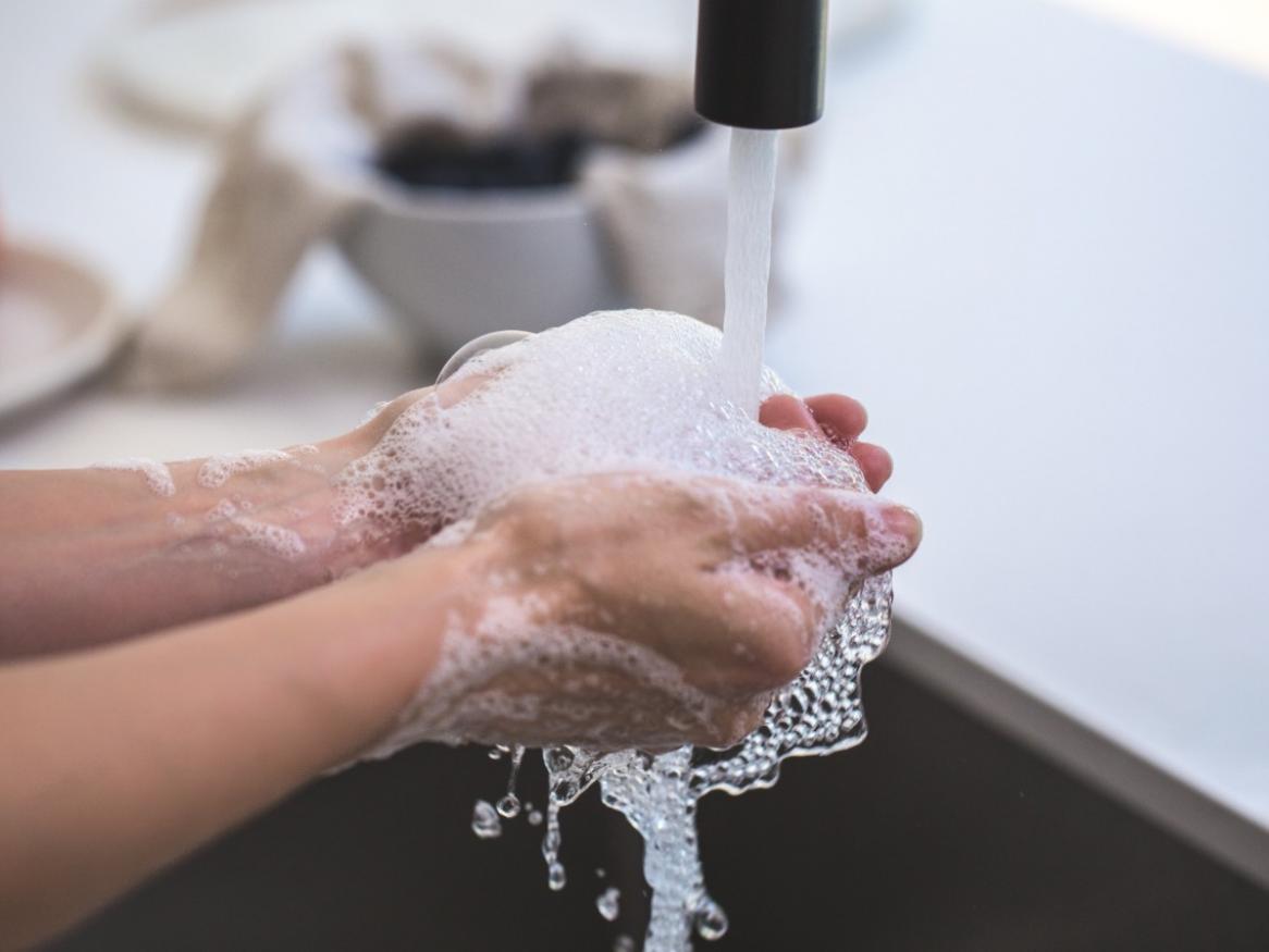 person washing their hands with water and hand soap